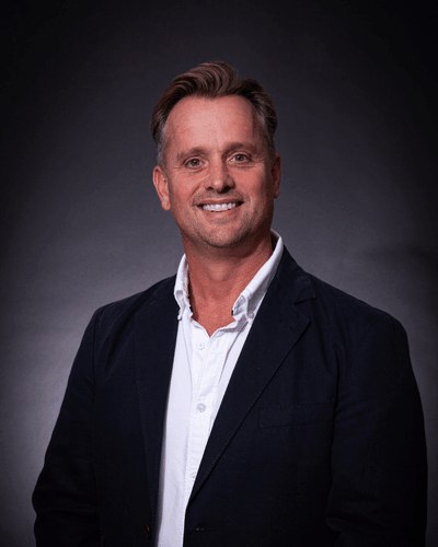 Portrait photo of Paul Sinclair, wearing a white shirt and dark blazer