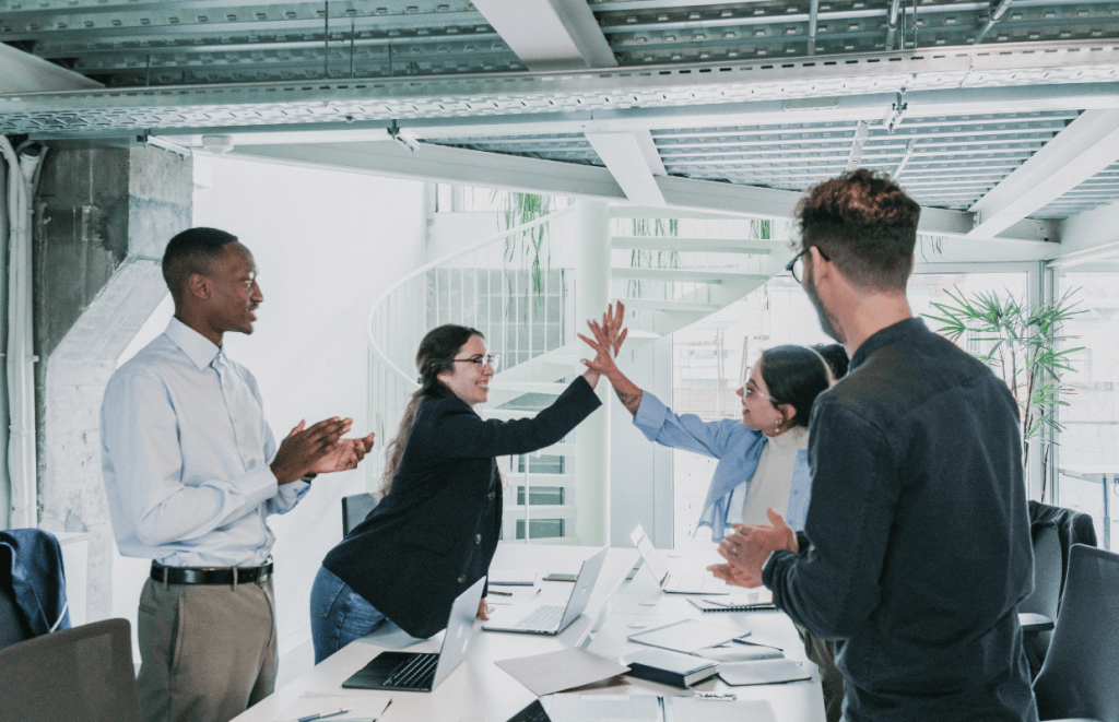 NI Increase: Team of people giving high fives over a table